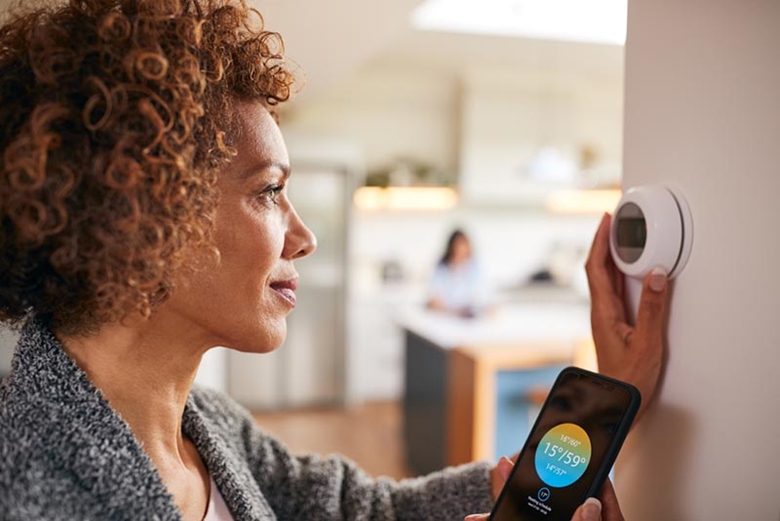 Woman adjusting a smart thermostat